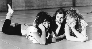 Three young women laugh while lying on the floor