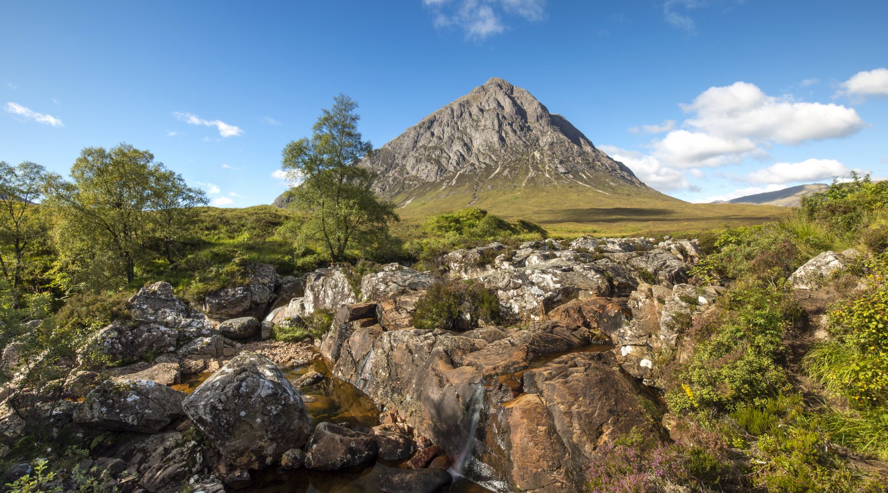 Stream with pyramid shaped mountain and blue sky west higland way