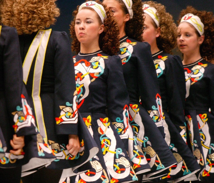 A line of curly red headed young girls in colourful Irish Dancing Costumes and headbands