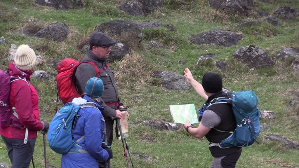 Mountain Guide teaching navigation map to a group on the mountainside